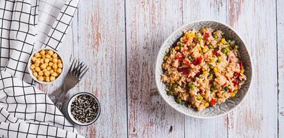 A bowl of cooked rice and vegetables for garnish on the table top view web banner photo