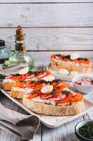 Appetizing bruschetta with ricotta, tomato, radish and quail egg on a plate vertical view photo