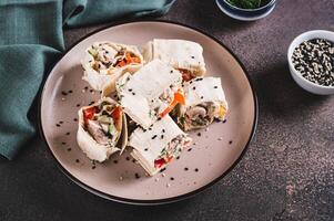 Flat bread rolls with chicken and vegetables on a plate on the table photo