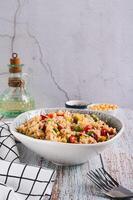 Homemade fried rice with peas, corn and pepper in a bowl on the table vertical view photo