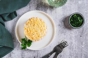 Traditional layered salad with canned fish on a plate on the table top view photo