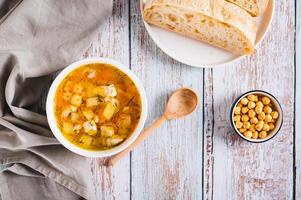 Fresh chicken soup with vegetables in a bowl on the table top view photo