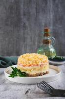 Traditional layered salad with canned fish on a plate on the table vertical view photo