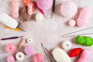 Frame of colored balls of wool and cotton, hooks and knitting needles on the table top view photo