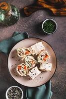 Flat bread rolls with chicken and vegetables on a plate on the table top and vertical view photo