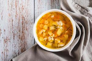 Close up of fresh chicken soup with vegetables in a bowl on the table top view photo