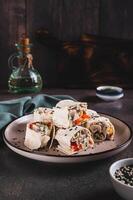 Chicken meat, pepper and cucumber in sauce wrapped in tortilla rolls on a plate vertical view photo
