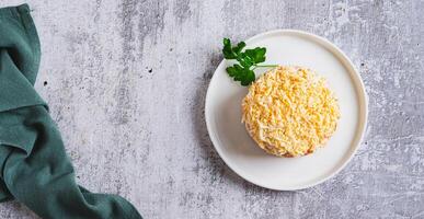 Classic mimosa salad with canned fish and vegetables on a plate on the table top view web banner photo