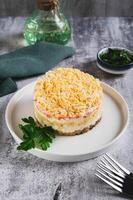 Classic mimosa salad with canned fish and vegetables on a plate on the table vertical view photo