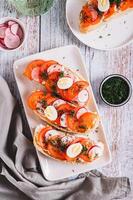 Sandwiches with ricotta, tomato, radish and egg on a plate on a table top and vertical view photo