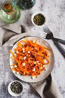 Homemade carrot slices in spices with ricotta and pumpkin seeds on a plate top and vertical view photo