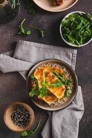 Grilled halloumi and arugula sandwich on a plate on a table top and vertical view photo