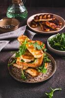 Grilled halloumi and arugula sandwich on a plate on a table vertical view photo