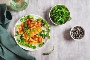 Warm salad with grilled halloumi and arugula on a plate on the table top view photo