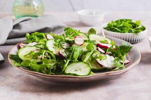 Vegetarian salad with cucumber, radish and arugula on a plate on the table photo
