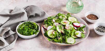 Vegetarian salad with cucumber, radish and arugula on a plate on the table web banner photo