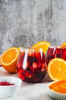 Refreshing summer sangria cocktail with fruits and berries in glasses on the table vertical view photo