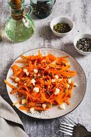 Homemade carrot slices in spices with ricotta and pumpkin seeds on a plate vertical view photo