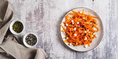 Homemade carrot slices in spices with ricotta and pumpkin seeds on a plate top view web banner photo