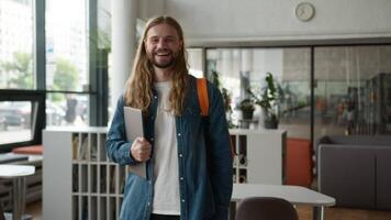 caucasiano aluna cara homem masculino posando dentro universidade Faculdade Academia corredor corredor segurando computador portátil sorridente feliz olhando às Câmera estudando Aprendendo Educação sorrir em pé dentro corredor sorrir dentro de casa video