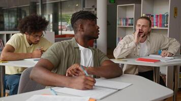 três multirracial alunos estudando Aprendendo dentro classe lição caucasiano cara Perguntando questão estude problema falando mostrando Está bem diversidade homens rapazes escrevendo tarefa dentro universidade Faculdade dentro Sala de aula Educação video