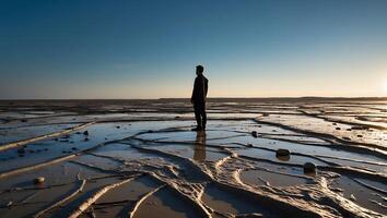 Man Standing on Tidal Flat Reflecting Sunset Light in Calm Setting photo