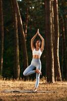Evening ,warm up exercises. Woman, is ,,,doing yoga fitness exercises in the forest photo