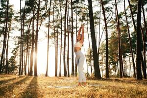 Stretching up,,, warm up exercises. Woman is doing yoga fitness exercises in the forest photo