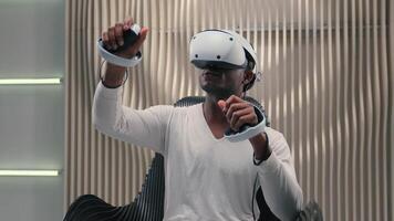 African American ethnic man male guy playing VR game innovation internet gaming interactive cyberspace interface in futuristic studio wearing virtual reality glasses helmet hold controllers futurism video