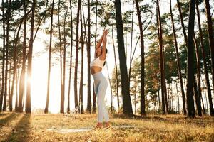 Stretching ,up, warm up exercises. Woman is doing yoga fitness exercises in the forest photo
