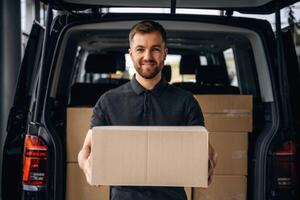 Holding the packed product in hands..., Delivery man or loader is near the car with a box photo