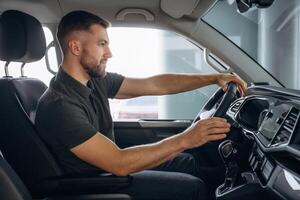 View from, the side. Man, is ,sitting in the car, driver photo