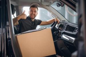 Showing, hand, gesture, everything is fine, will be done. The delivery man or a loader is in the car with box photo
