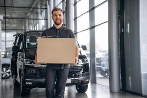 Smiling, ,positive facial ,expression.... Delivery man or loader is near the car with a box photo