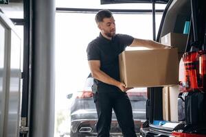Delivery man or loader is ,near, the, car with a box photo