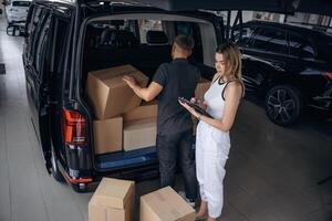 Woman ,is ,helping delivery man with products, holding notepad, loader is working with boxes from automobile photo