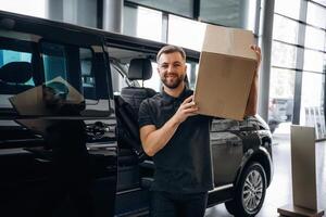 Box is on the shoulder. Delivery man ,or loader is near the car with photo