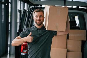 Box is ,on, the shoulder. Delivery man or loader is near the car with photo