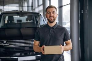 Here's your delivery... Man loader is near the car with a box photo
