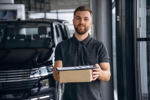 Front view, standing.,,, Delivery man or loader is near the car with a box photo