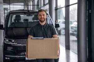 Smiling,,, positive facial expression., Delivery man or loader is near the car with a box photo