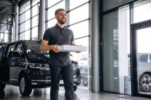 Delivery ,man or loader,, is near the car with a box photo