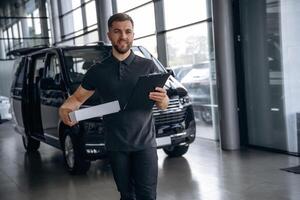 Business of, delivery, with notepad. Man loader is near the car with a box photo