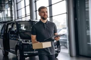 Fast ,,delivery service, standing. Man loader is near the car with a box photo