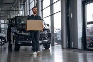 Smiling,, positive facial expression. Delivery man or loader is near the car with a box photo