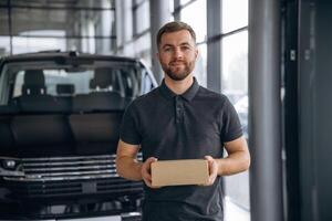 Here's, your delivery. Man loader is near the car with a box photo