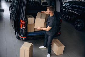 Unloading the ,,boxes. Delivery man or loader is near the car photo
