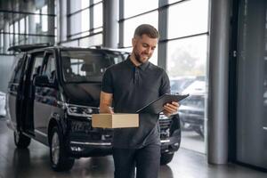 Fast ,delivery service, standing. Man loader is near the car with a box photo