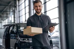 Fast, delivery service, standing. Man loader is near the car with a box photo