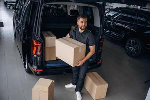 Unloading the ,boxes. Delivery man or loader is near the car photo